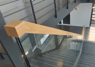 Metalltreppe mit Glasgeländer und Holzhandlauf
