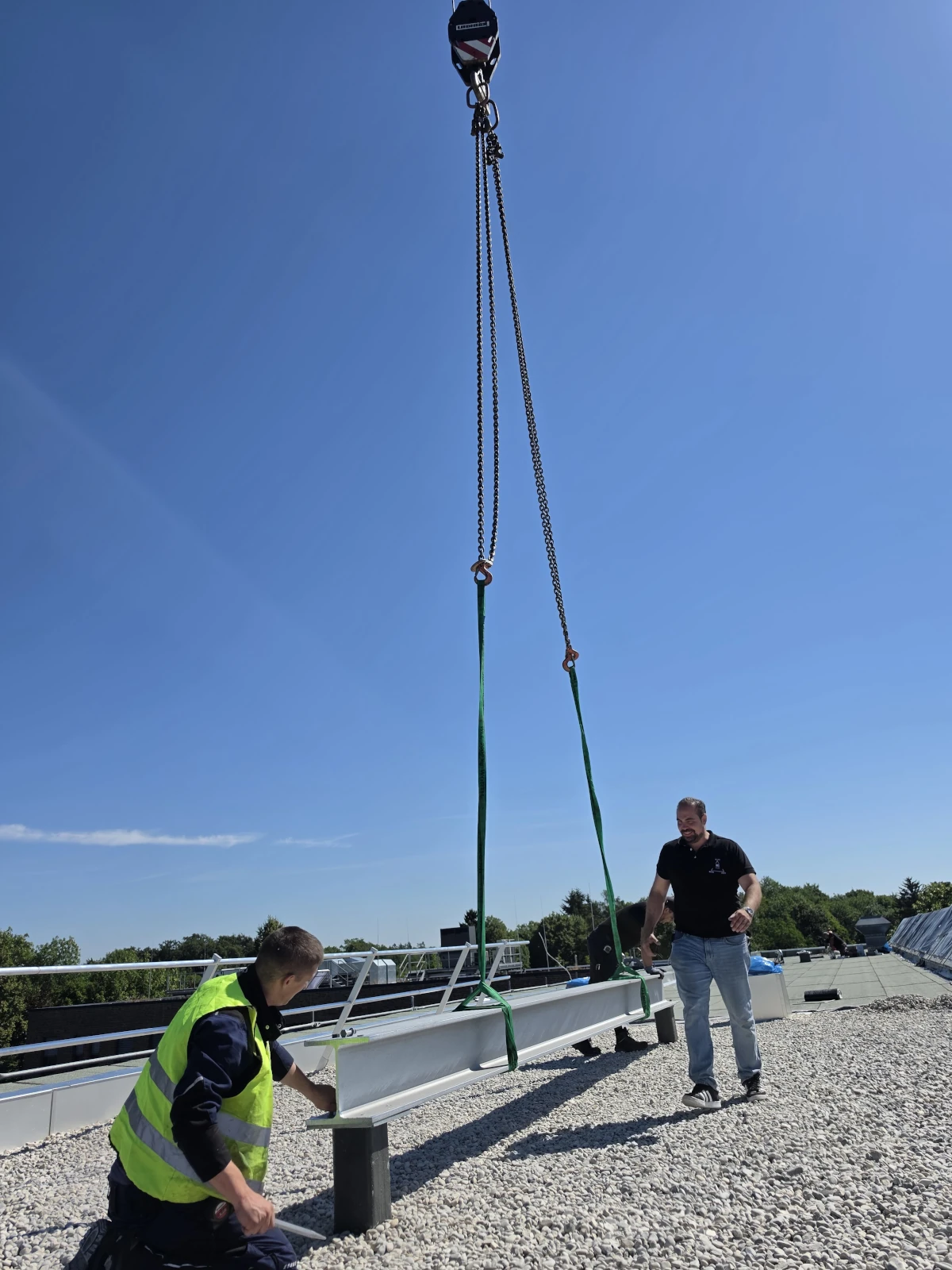 Montage eines Stahlträgers auf der Baustelle Mitarbeiter von IWS bei der Montage eines Stahlträgers mit Kranunterstützung